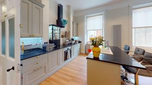 a kitchen with white cabinets and a black counter top at The Dulwich in Cheltenham