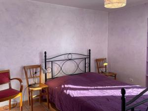 a bedroom with a bed with purple sheets and two chairs at Gîte indépendant à Saint-Genest avec jardin clos - FR-1-489-562 in Saint-Genest