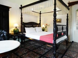 1 dormitorio con cama con dosel y manta roja en WelcomHeritage Panjim Inn, en Panaji
