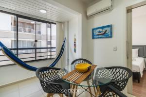 a room with a glass table and chairs and a hammock at Apto c/ Churrasqueira 450m da Praia PNM0202 in Florianópolis
