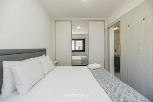 a bedroom with a white bed and a mirror at Apto c/ Churrasqueira 450m da Praia PNM0202 in Florianópolis