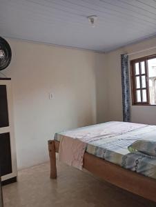 a bedroom with a bed in a room with a window at Casa Amarela in São Francisco do Sul