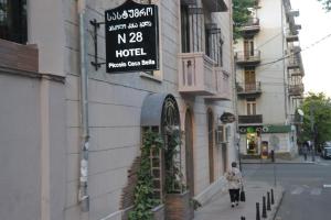 a woman walking down a street in front of a hotel at Piccolo casa bella in Tbilisi City