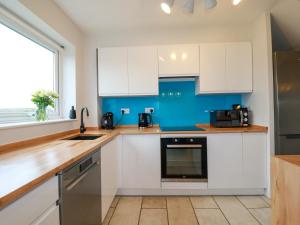 a kitchen with white cabinets and a blue wall at Estuary View in Newquay +23 photos