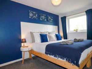 a blue bedroom with a bed with a blue wall at Estuary View in Newquay