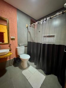 a bathroom with a toilet and a black shower curtain at Pousada Águas do Jalapão in Ponte Alta do Norte