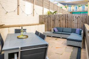 a patio with a table and chairs and a couch at Jollys-Contemporary Beachfront Property, Pet Friendly with optional Hot Tub in Sandown