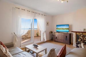 Una sala de estar con un sofá y un televisor. en Casa Feliz Penthouse by Mabiente Properties, en La Cala de Mijas