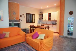 ein Wohnzimmer mit 2 orangenen Stühlen und eine Küche in der Unterkunft Villa Pergola in San Michele Salentino