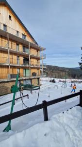 a playground in the snow in front of a building at Apartmán Ski & Bike Janské Lázně in Janske Lazne