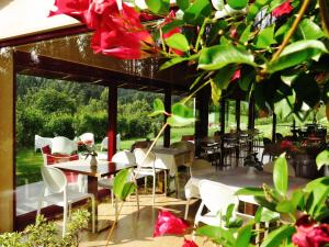 un restaurante con sillas y mesas blancas y flores rojas en Hotel El Castaño Dormilón en Santa Marta de Ortigueira