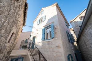 a stone building with blue windows and a staircase at Apartment Villa IV in Trogir