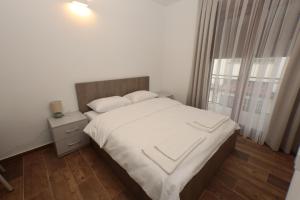 a bedroom with a bed with white sheets and a window at Livinn Apartments-Superior Apartment in Prizren