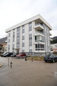 a large building with cars parked in a parking lot at Apartman Ruzica in Trebinje