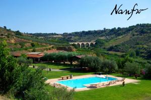 a swimming pool in the middle of a lush green field at Nanfro Resort - Masseria Spaccaforno in Caltagirone