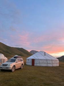 a car parked in a field with two tents at Kel-Suu yurt camp in Kol-Suu