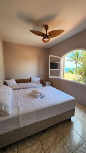 a bedroom with a bed with a ceiling fan and a window at Pousada Flor de Lótus Caraguá in Caraguatatuba