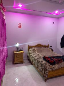 una camera con letto e comodino con luci viola di غرفة الاسطورة a Oujda