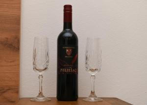 a bottle of wine next to two wine glasses at Apartman Ruzica in Trebinje +3 photos