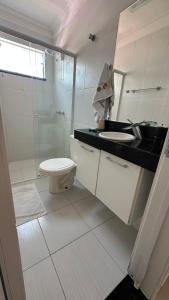 a white bathroom with a sink and a toilet at Bombinhas Summer Beach - Praia de Bombas apartamento in Bombinhas +14 photos