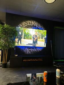 un grande schermo TV con un uomo che gioca a un videogioco di Love&love room a Les Clayes-sous-Bois
