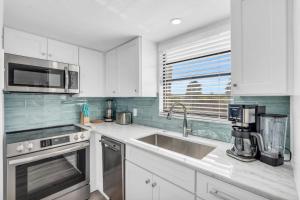 a kitchen with white cabinets and a sink at Fantastic Views - A Fully Renovated Deluxe Condo W Private Beach Access in Naples