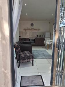 a living room with a chair and a kitchen at Comfey Stay in Somerset West +7 photos
