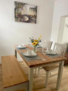 a wooden table with two chairs and a table with wine glasses at Cozy two bedroom home with historic significance in Saint Neots