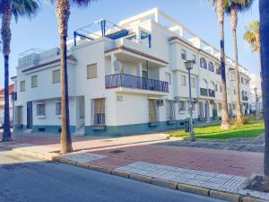 biały budynek z palmami przed nim w obiekcie Top Rota Playa La Costilla Costa de la Luz w mieście Rota