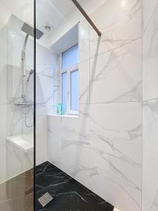 a glass shower in a white bathroom with a window at Cosy Apartment Uccle 3 in Brussels