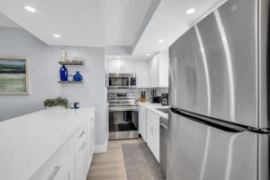 ネープルズにあるDeluxe Condo - Amazing Viewsの白いキャビネットとステンレス製の冷蔵庫を備えたキッチン +47枚の写真