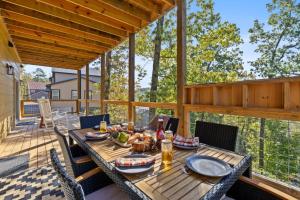 a dining table on a deck with a view of trees at Sweet Escape By Ghosal Luxury Lodging in Gatlinburg