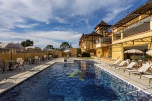 a pool with chairs and tables and a building at Hotel Le Renard - Campos do Jordao in Campos do Jordão
