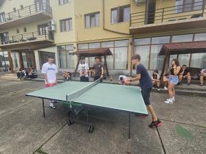 a group of people standing around a ping pong table at Hostel Restaurant Ciuperca in Hunedoara