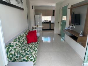 ein Wohnzimmer mit einem Sofa und einem roten Kissen in der Unterkunft Apartamento de praia em Barra Grande in Maragogi + 7 Fotos