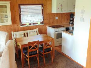 a kitchen with a table and chairs and a refrigerator at Bungalow in Damshagen nahe der Ostsee in Reppenhagen +32 photos