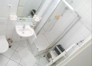 a white bathroom with a sink and a shower at Ferienwohnung Möwe mit Balkon und einem Strandkorb im Sommer in Zempin