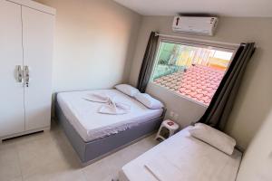 ein kleines Zimmer mit zwei Betten und einem Fenster in der Unterkunft Apartamento de praia em Barra Grande in Maragogi