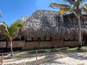 a building with a thatched roof and palm trees at Casitas en Vichayito, a Pasos de la Playa in Los Órganos