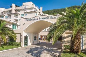 a building with a palm tree in front of it at Bombinhas Summer Beach - Praia de Bombas apartamento in Bombinhas