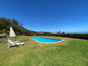 a chair and an umbrella next to a swimming pool at Casa Familiar en Jardín del Mar in Viña del Mar