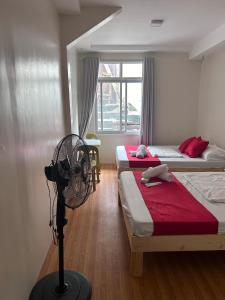 a room with two beds and a fan in it at Baden Powell Hostel in Baguio