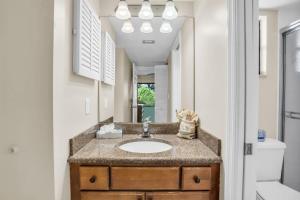a bathroom with a sink and a mirror at Walk From Lanai to Pool and More in Naples