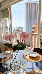 Una mesa con vasos y flores en un balcón. en Brisas de Levante, en Benidorm