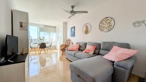 sala de estar con sofá gris y almohadas rosas en Brisas de Levante, en Benidorm