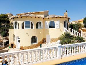 a house with a white fence next to a pool at "Traumhaftes Ferienhaus mit Pool und Meerblick - Cumbre del Sol erleben!" in Benitachell