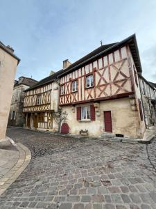 an old building with red doors on a cobblestone street at Gîte Le Saint Père in Avallon