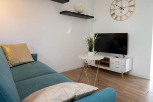 een woonkamer met een blauwe bank en een tv bij Lora apartment,free private parking, self check in in Como