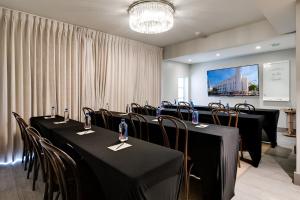 Una sala de conferencias con mesas y sillas negras y una pantalla. en The Plymouth South Beach, en Miami Beach 156 fotos más