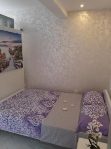 a small bedroom with a purple bed and a painting at Apartmani LaVa igalo 1 in Igalo